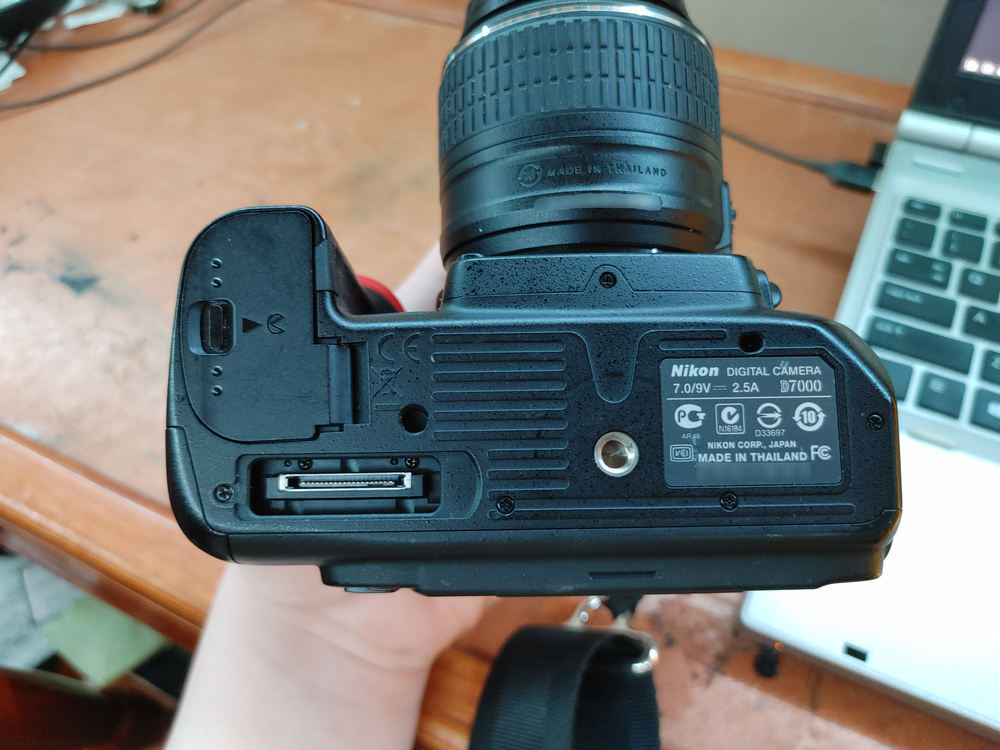 Bottom of the D7000, battery door on the left, with a flat multi-pin connector just below it