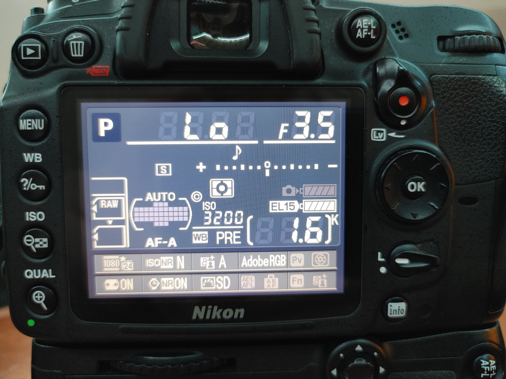Back of the D7000, on, with the screen showing the info display, showing all the numbers and current settings. On the right-hand side, there’s not one, but two battery icons, one with a camera icon pointing to it, that’s dimmed out, and another with “El15” pointing to it, that’s lit up.